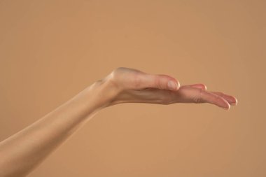Kadın eli ve açık avuç içi bej arka planda izole.