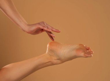 Perfect clean female feet . Beautiful and elegant groomed woman's hand touching her foot . Spa ,scrub and foot care.