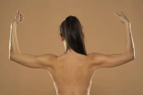 Back View Young Nude Woman Ponytail Showing Arms Beige Background — Zdjęcie stockowe