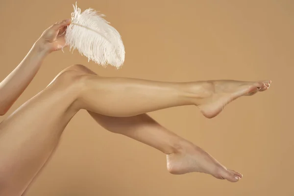 Ruka Mladé Ženy Dotýkající Nohou Bílým Peřím Béžovém Pozadí Krásné — Stock fotografie