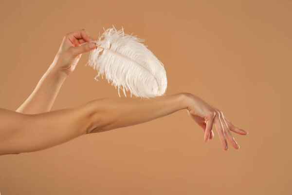 Young Woman Hand Touhing Her Skin White Feather Beige Background Royalty Free Stock Images
