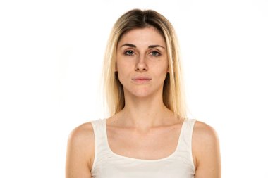 Beyaz bir arka plan üzerinde makyaj olmadan genç bir kadın portresi.