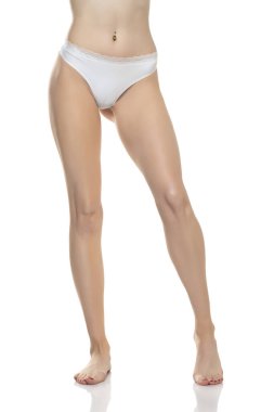 Beyaz bikini külotlu, beyaz stüdyo arka planında çıplak ayaklı kadın manzarası..