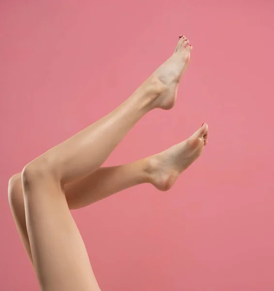 长而光滑的女人腿 与粉红背景隔离 — 图库照片