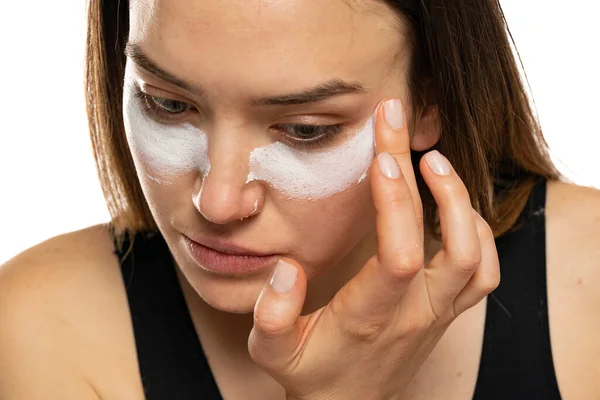 一个年轻女子在白色背景下在眼皮底下使用化妆品的肖像 — 图库照片