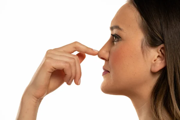 Junge Frau Berührt Ihre Nase Mit Dem Finger Auf Weißem — Stockfoto