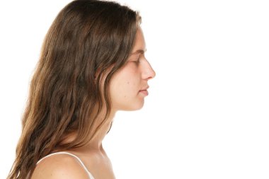 Profile of a young woman without makeup and closed eyes on a white background.