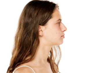 Profile of a young woman without makeup on a white background.