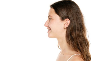 Profile of a young smiling woman without makeup on a white background.