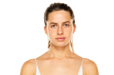 Portrait of a young woman with tied hair and without makeup on a white background.