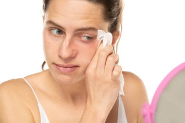 A young happy woman removing makeup with the wet tissues  on white studio background.