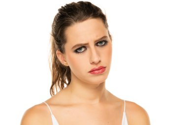 Beautiful unhappy woman with make up and tied hair on a white background.