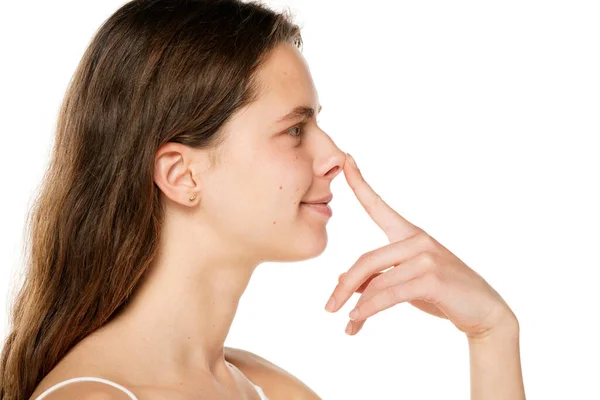 Genç Gülümseyen Bir Kadın Beyaz Bir Arka Planda Parmağını Burnuna — Stok fotoğraf