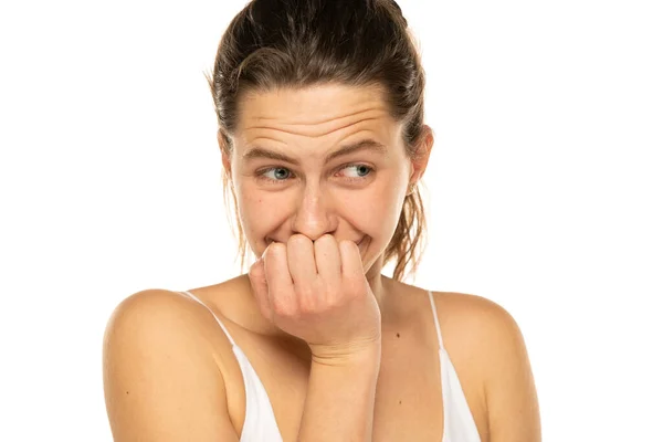 Embarrassed young woman laughing and covering mouth with hand on a white background.