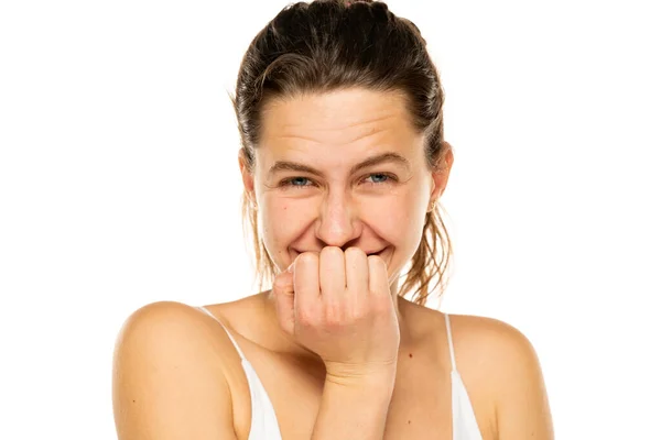 Embarrassed young woman laughing and covering mouth with hands on a white background.