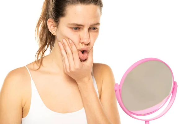 Worried Young Woman Front Mirror Squeezing Her Mouth White Background — Stockfoto