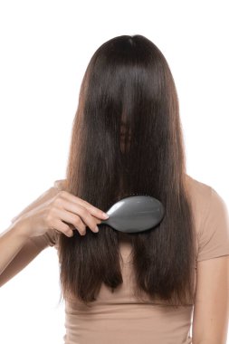 A woman combing the hair over her face on a white studio background.