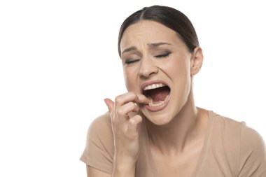 Beautiful young woman shows on the aching tooth on a white studio background.