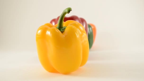Žluté, červené, zelené a oranžové papriky proti bílé - linie uspořádání - dolly vlevo — Stock video