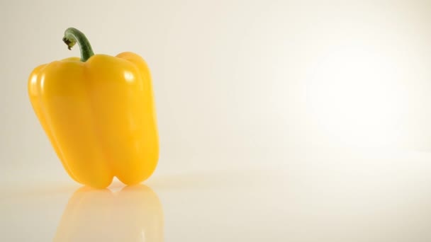 Roterande gul paprika på akryl mot vit - dolly vänster — Stockvideo