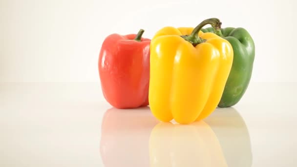 Gelbe, grüne und rote Paprika auf Acryl gegen Weiß - Dreieck-Anordnung - Dolly links — Stockvideo