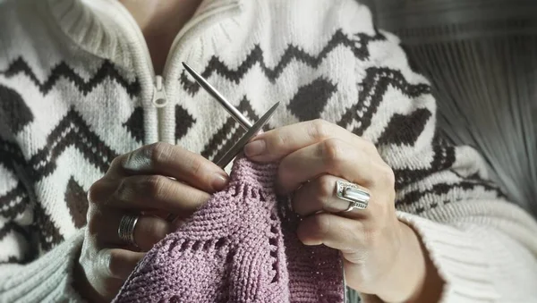 woman hands with a knitted sweater and a scarf with a white blanket.Woman knitting a sweater, a piece of fabric