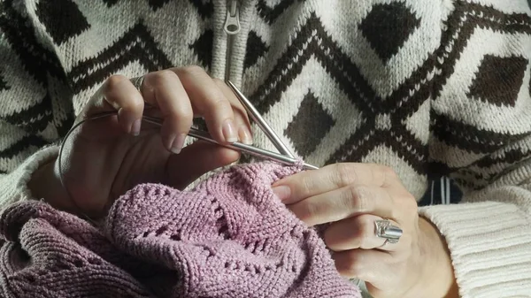 woman hands with knitting needles on a white background.Woman knitting a sweater, a piece of fabric