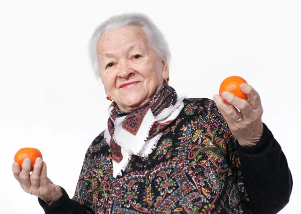 Elderly woman holding two tangerines i — Stock Photo, Image