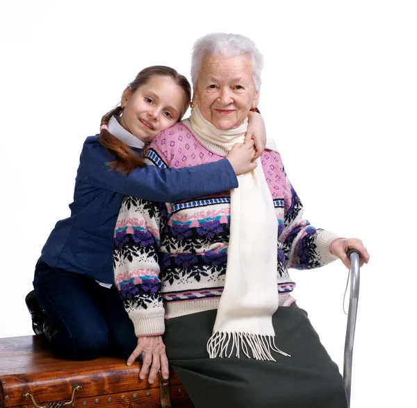 Söt flicka sitter på en låda och kramar hennes mormor — Stockfoto