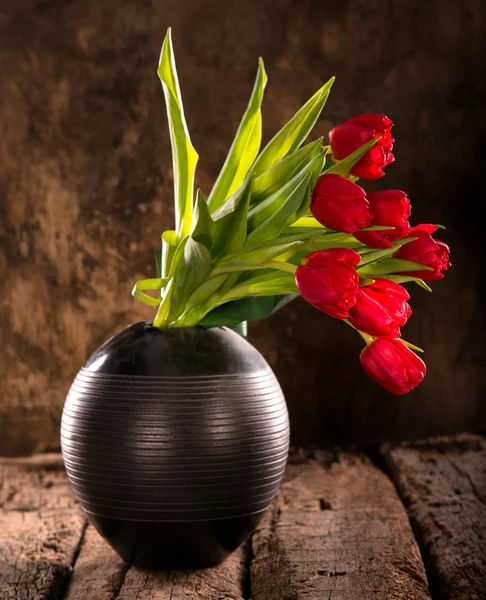 Piękne czerwone tulipany w wazonie czarny — Zdjęcie stockowe
