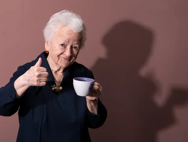Stara kobieta cieszy kubek kawy lub herbaty — Zdjęcie stockowe
