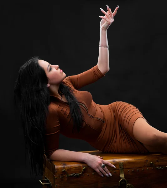 Sexy woman laying on a wooden chest — Stock Photo, Image