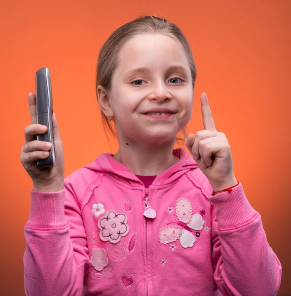 Girl holding a phone and pointing up — Stock Photo, Image