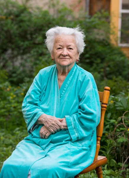 Sorridente vecchia donnaseduta su una sedia — Foto Stock