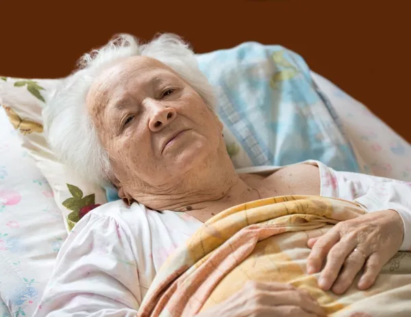 Стара жінка лежить в ліжку Стокове Зображення