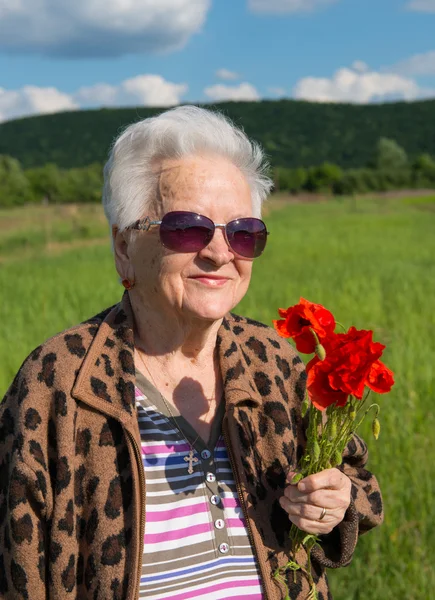 Elderly woman in sunglasses with bunch of poppies — Stock Photo, Image
