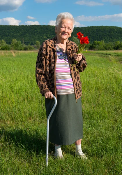 Mulher velha com cacho de flores de papoula — Fotografia de Stock