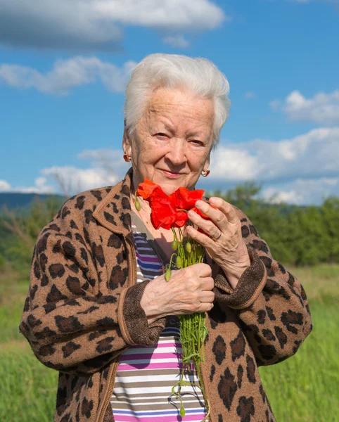 Mulher velha com papoilas — Fotografia de Stock