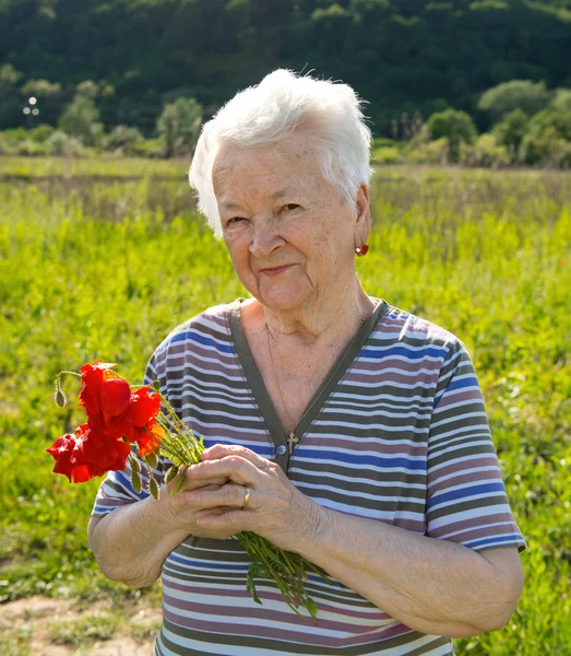 Stará žena s máky — Stock fotografie