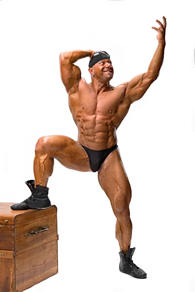 Bodybuilder posing near wooden chest — Stock Photo, Image