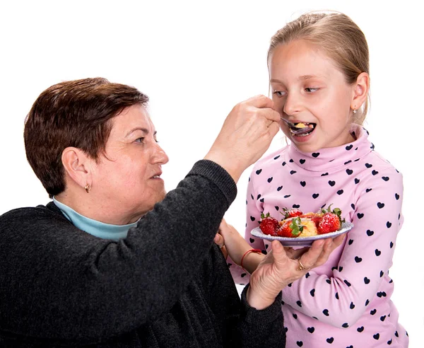 Grandmother feeds strawberry pie to her granddaughter — Stock Photo, Image