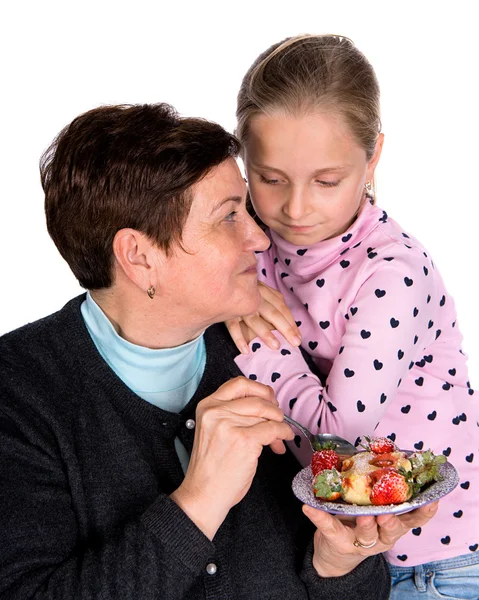 Grandmother feeds strawberry to her granddaughter — Stock Photo, Image