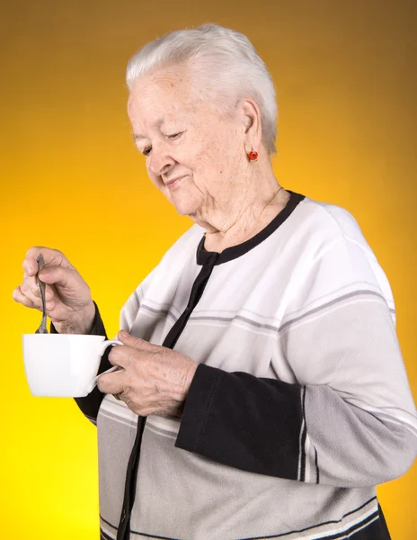 Стара жінка насолоджується чашкою кави або чаю — стокове фото