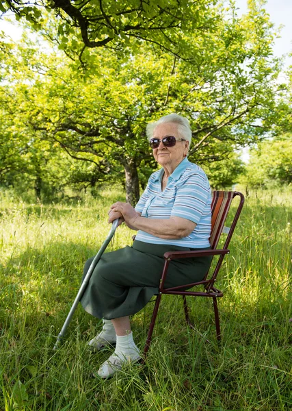 Gammal kvinna sitter på en stol — Stockfoto