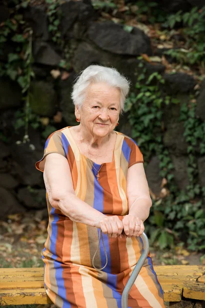 Old woman sitting on a bench — Stock Photo, Image