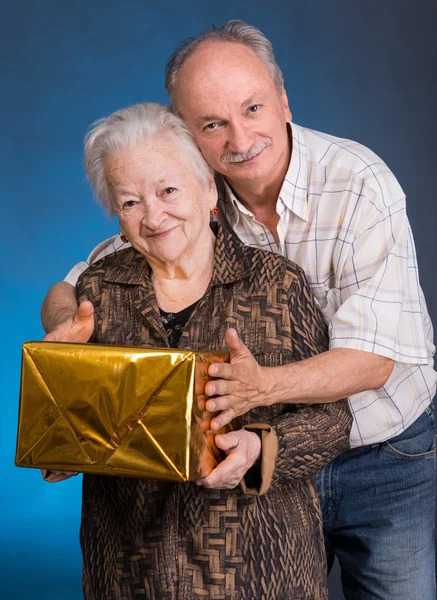 Un figlio adulto e mamma anziana con scatola regalo — Foto Stock