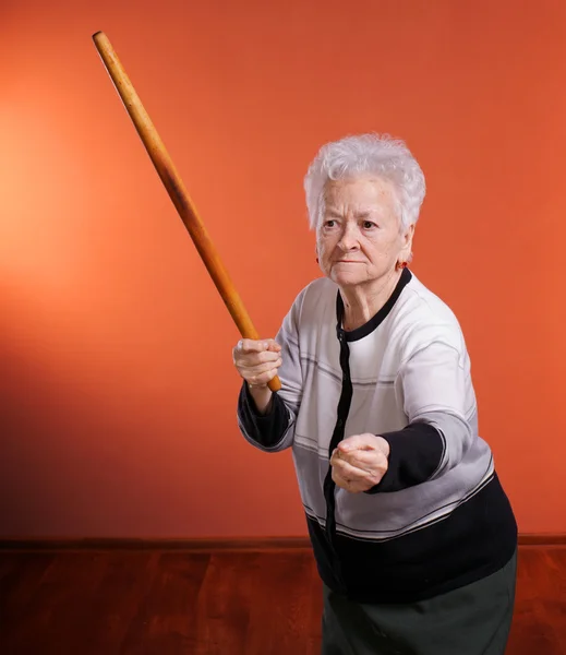 Старая сердитая женщина угрожает скалкой — стоковое фото
