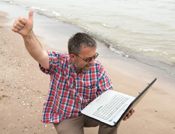 Emotionele zakenman met laptop op het strand — Stockfoto