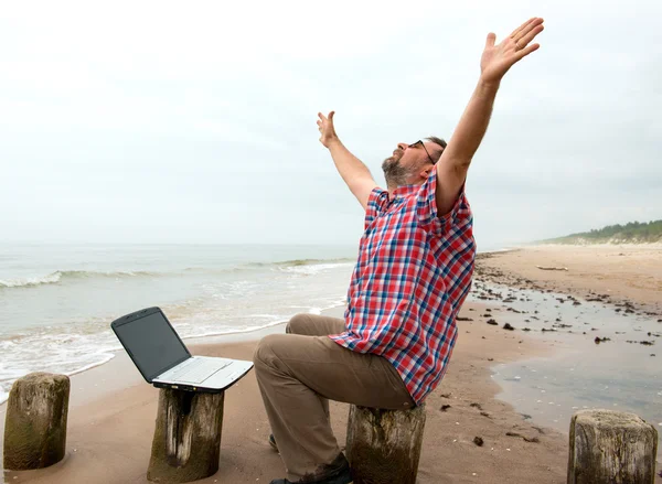 Emotional businessman with laptop on the beach — Stock Photo, Image