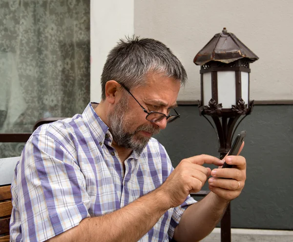 Homem idoso usando um telefone inteligente — Fotografia de Stock